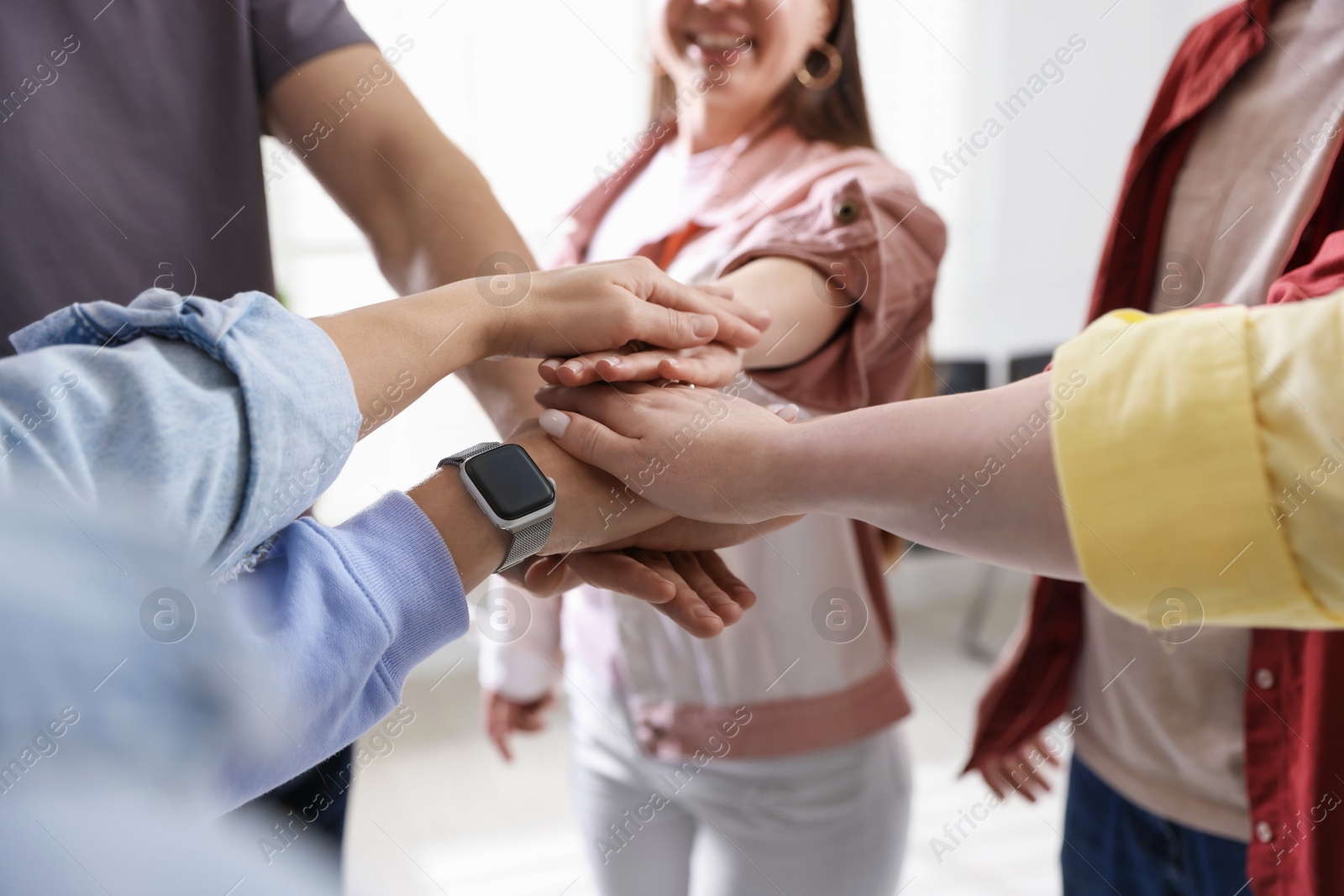 Photo of Unity concept. People holding hands together indoors, closeup