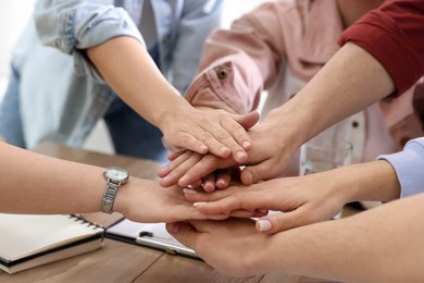 Unity concept. People holding hands together at wooden table indoors, closeup