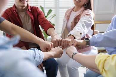 Photo of Unity concept. People holding fists together indoors, closeup