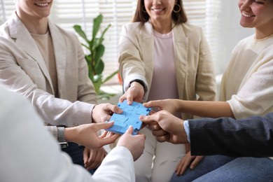 Unity concept. People putting puzzle pieces together indoors, closeup