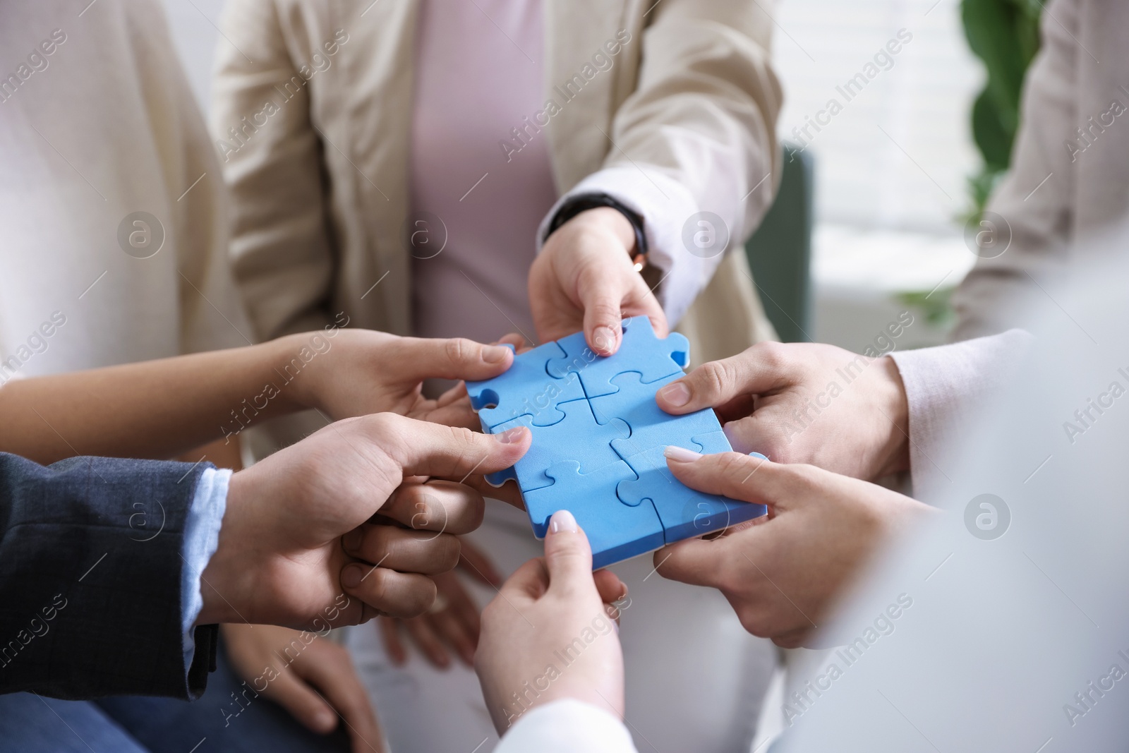 Photo of Unity concept. People putting puzzle pieces together indoors, closeup