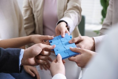 Photo of Unity concept. People putting puzzle pieces together indoors, closeup