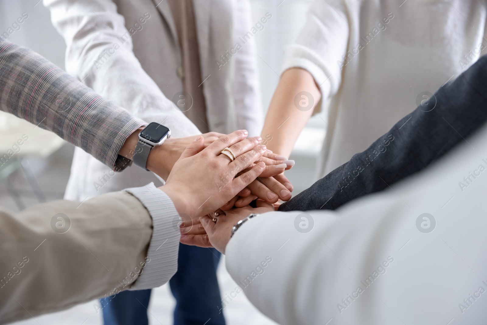 Photo of Unity concept. People holding hands together indoors, closeup