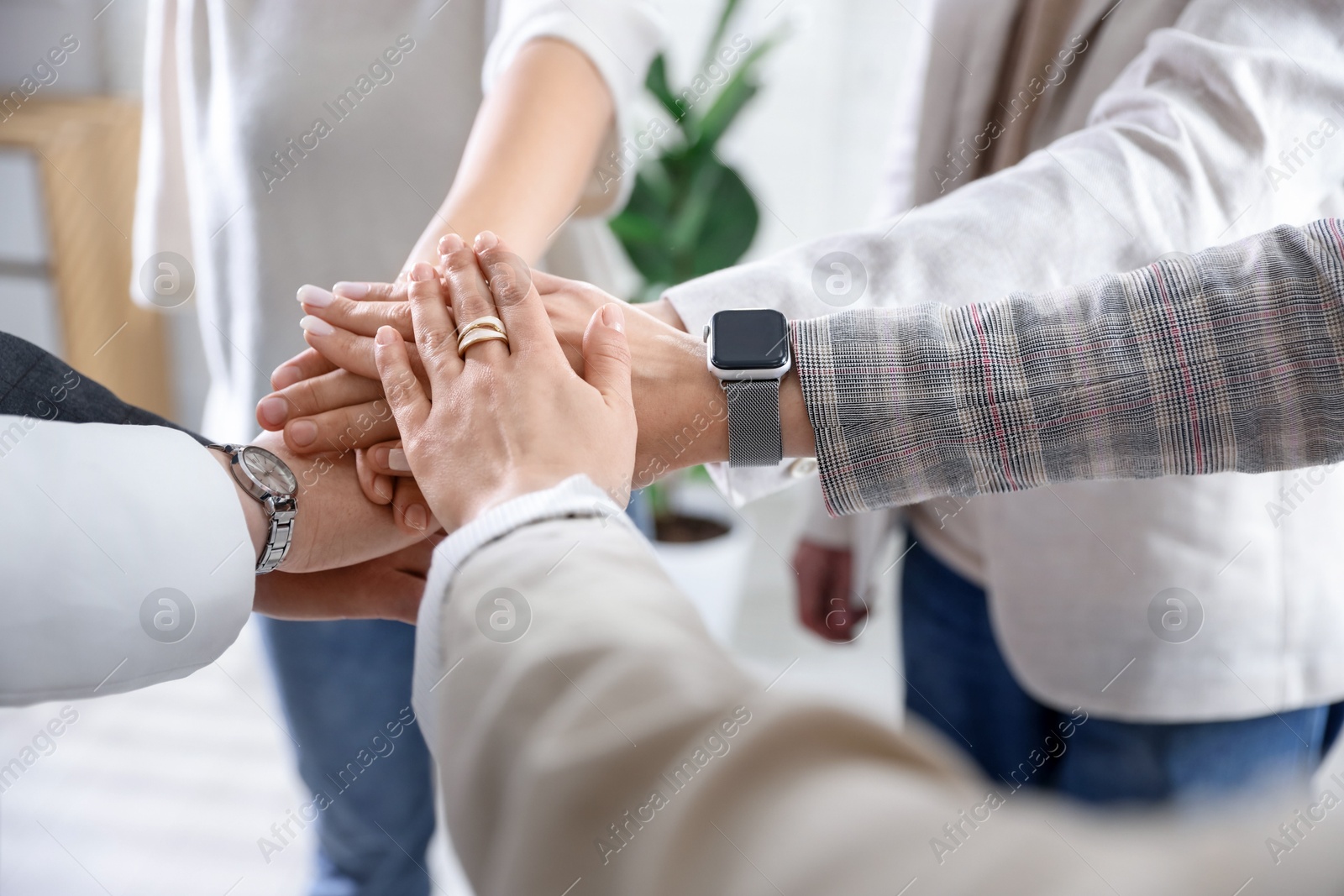 Photo of Unity concept. People holding hands together indoors, closeup