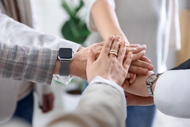 Photo of Unity concept. People holding hands together indoors, closeup