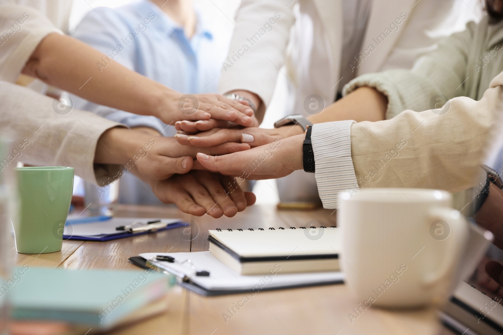 Photo of Unity concept. People holding hands together at table indoors, closeup