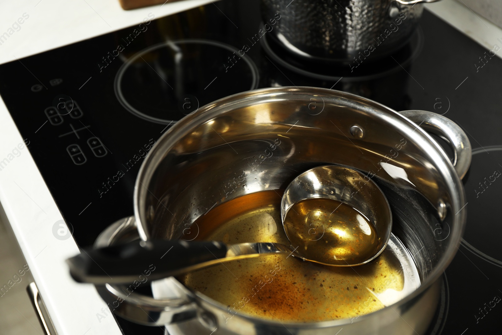 Photo of Used cooking oil and ladle in saucepan on stove