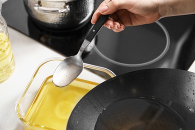 Photo of Woman pouring used cooking oil at white countertop, closeup