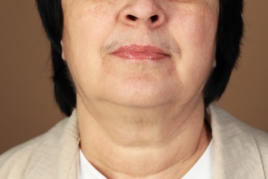 Photo of Senior woman with mustache on brown background, closeup