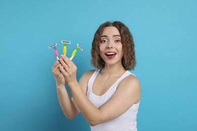 Photo of Happy woman with different razors on light blue background. Hair removal tools