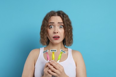 Emotional woman with different razors on light blue background. Hair removal tools