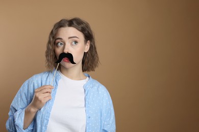 Photo of Woman with fake paper mustache on beige background. Space for text