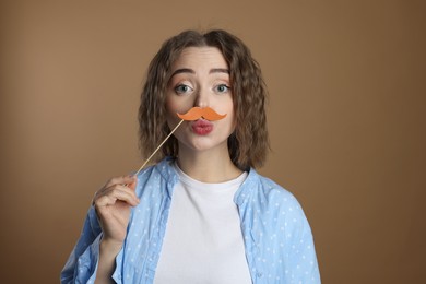 Funny woman with fake paper mustache on beige background