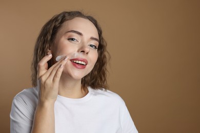 Photo of Happy woman removing her mustache with wax strip on beige background. Space for text