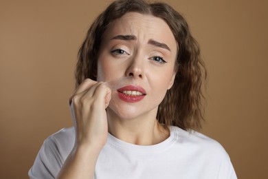 Photo of Emotional woman removing her mustache with wax strip on beige background