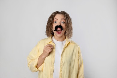 Photo of Emotional woman with fake paper mustache on grey background