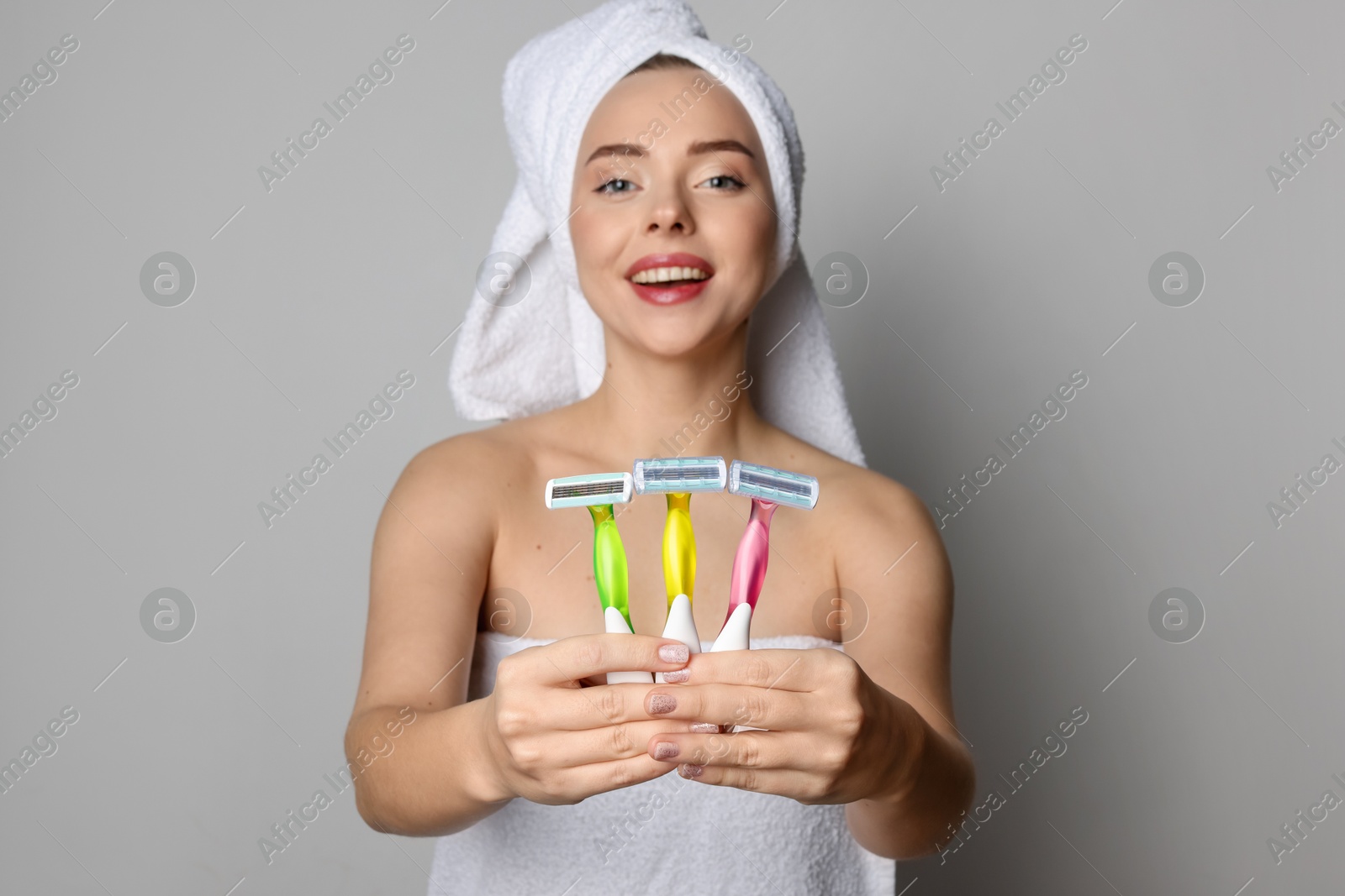 Photo of Happy woman with different razors on grey background. Hair removal tools