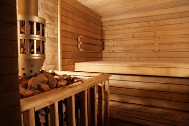 Photo of Wooden sauna with bench, stove and hot stones