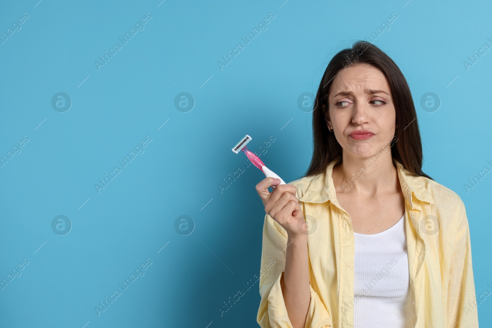 Photo of Beautiful woman with razor on light blue background, space for text. Hair removal tool