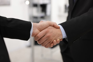 Photo of Businessmen shaking hands in agreement indoors, closeup