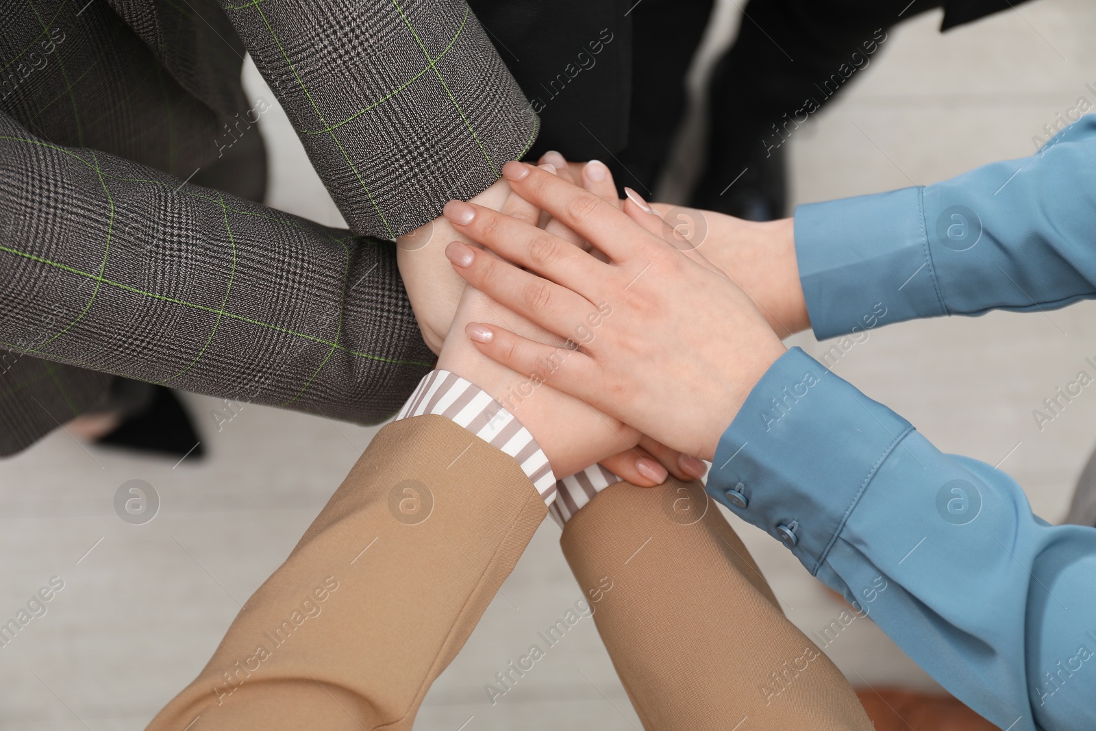 Photo of Business concept. Group of people stacking hands indoors, above view