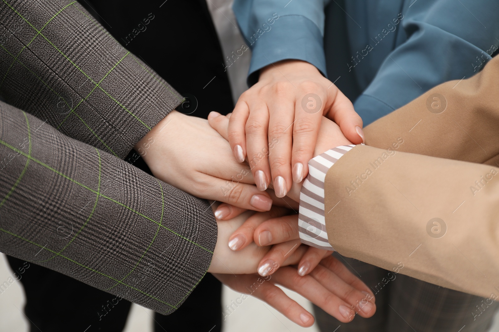 Photo of Business concept. Group of people stacking hands indoors, closeup