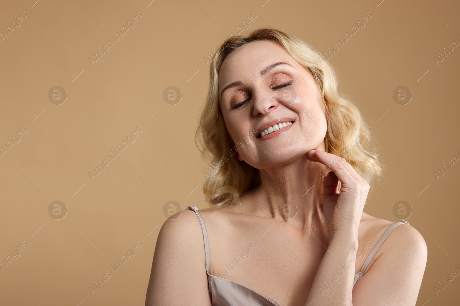 Photo of Smiling middle aged woman on beige background. Space for text