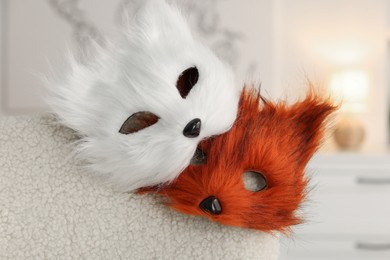 Photo of Quadrobics. Fox and cat masks on armchair indoors