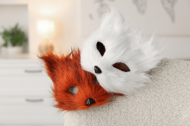 Photo of Quadrobics. Fox and cat masks on armchair indoors