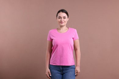 Woman in pink t-shirt on dark beige background. Mockup for design