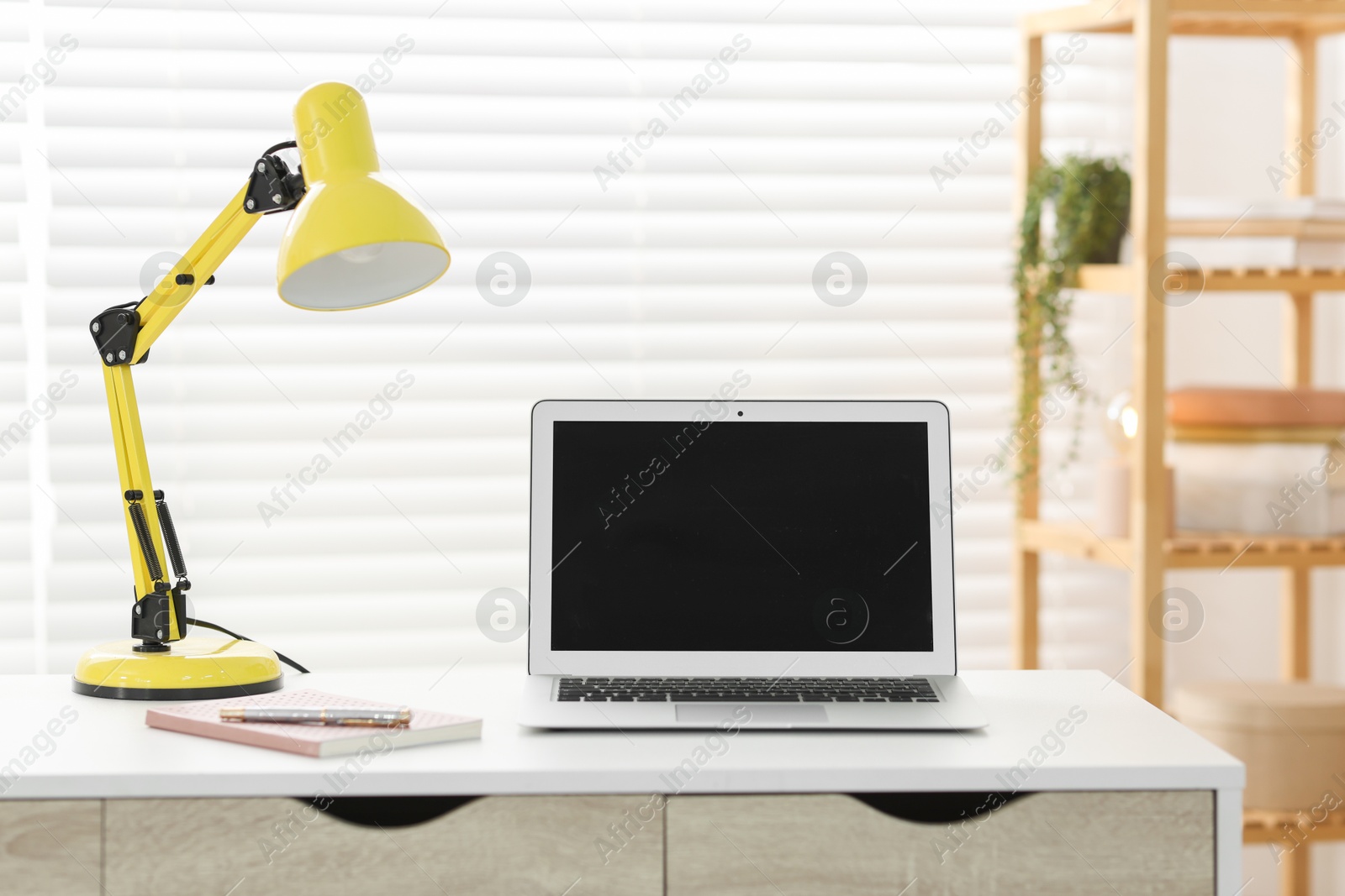 Photo of Home office. Comfortable workplace with laptop and lamp on desk indoors