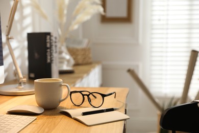 Photo of Comfortable workplace with computer, drink and glasses in home office, closeup