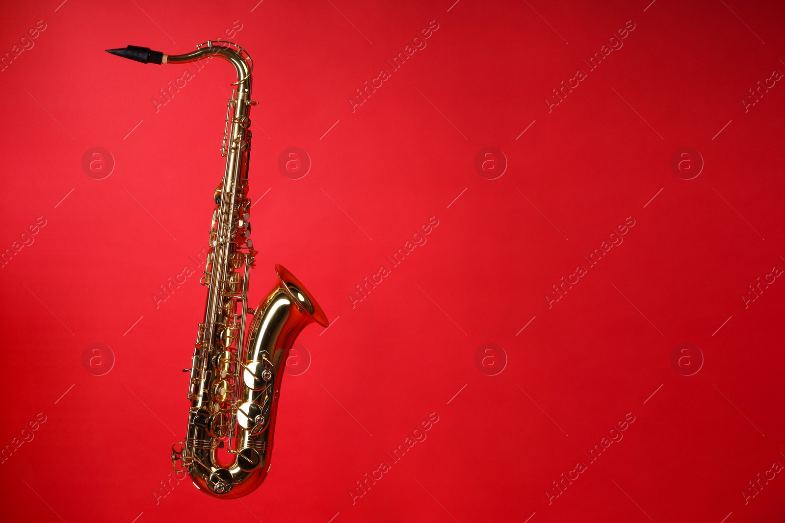 Photo of Jazz. One beautiful saxophone on red background, space for text