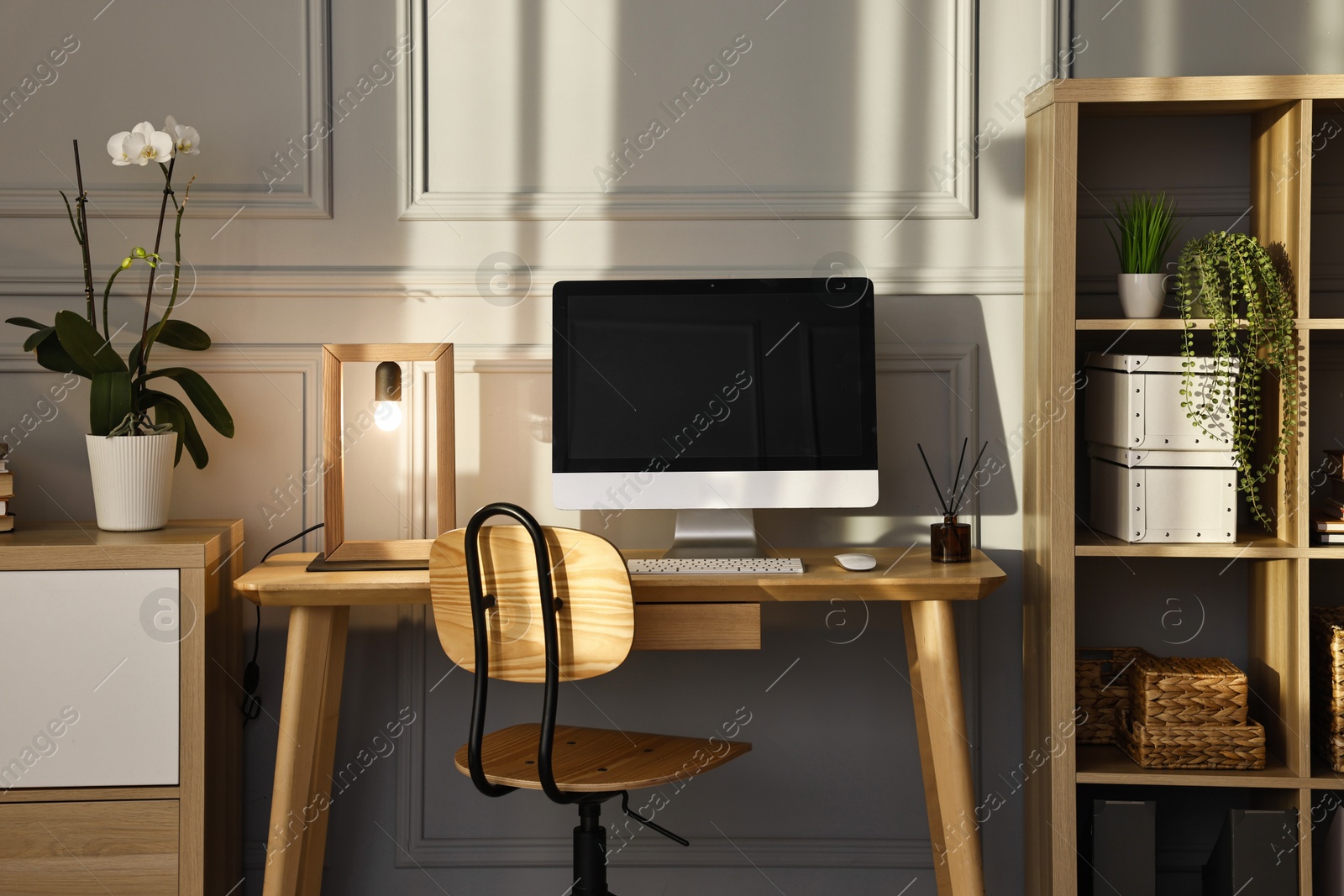 Photo of Comfortable workplace with modern computer and lamp on wooden desk in home office