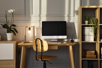 Photo of Comfortable workplace with modern computer and lamp on wooden desk in home office