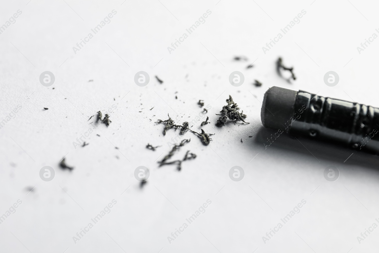 Pencil with eraser and scraps on white sheet of paper, closeup Photo of Pencil with eraser and scraps on white sheet of paper, closeup
