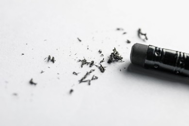 Photo of Pencil with eraser and scraps on white sheet of paper, closeup