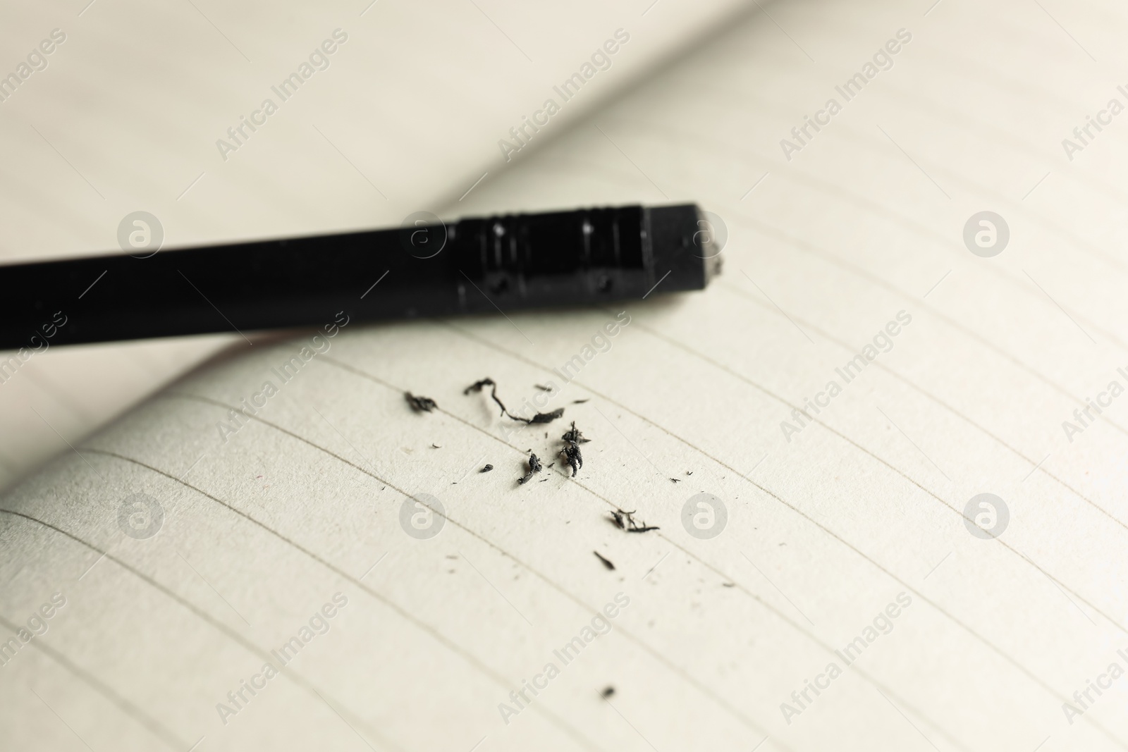 Photo of Pencil with eraser and scraps on copybook, closeup