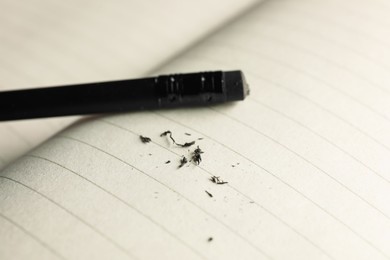 Photo of Pencil with eraser and scraps on copybook, closeup