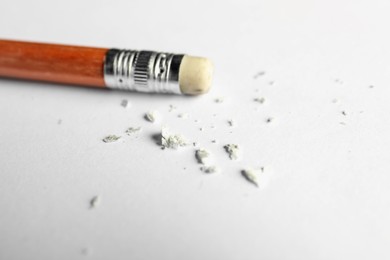 Photo of Pencil with eraser and scraps on white sheet of paper, closeup
