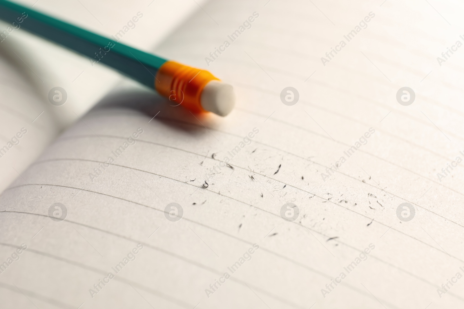 Photo of Pencil with eraser and scraps on copybook, selective focus