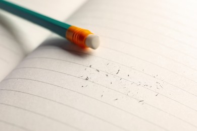 Photo of Pencil with eraser and scraps on copybook, selective focus