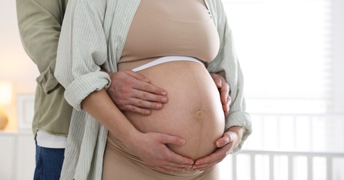 Photo of Pregnant woman and her husband at home, closeup. Space for text