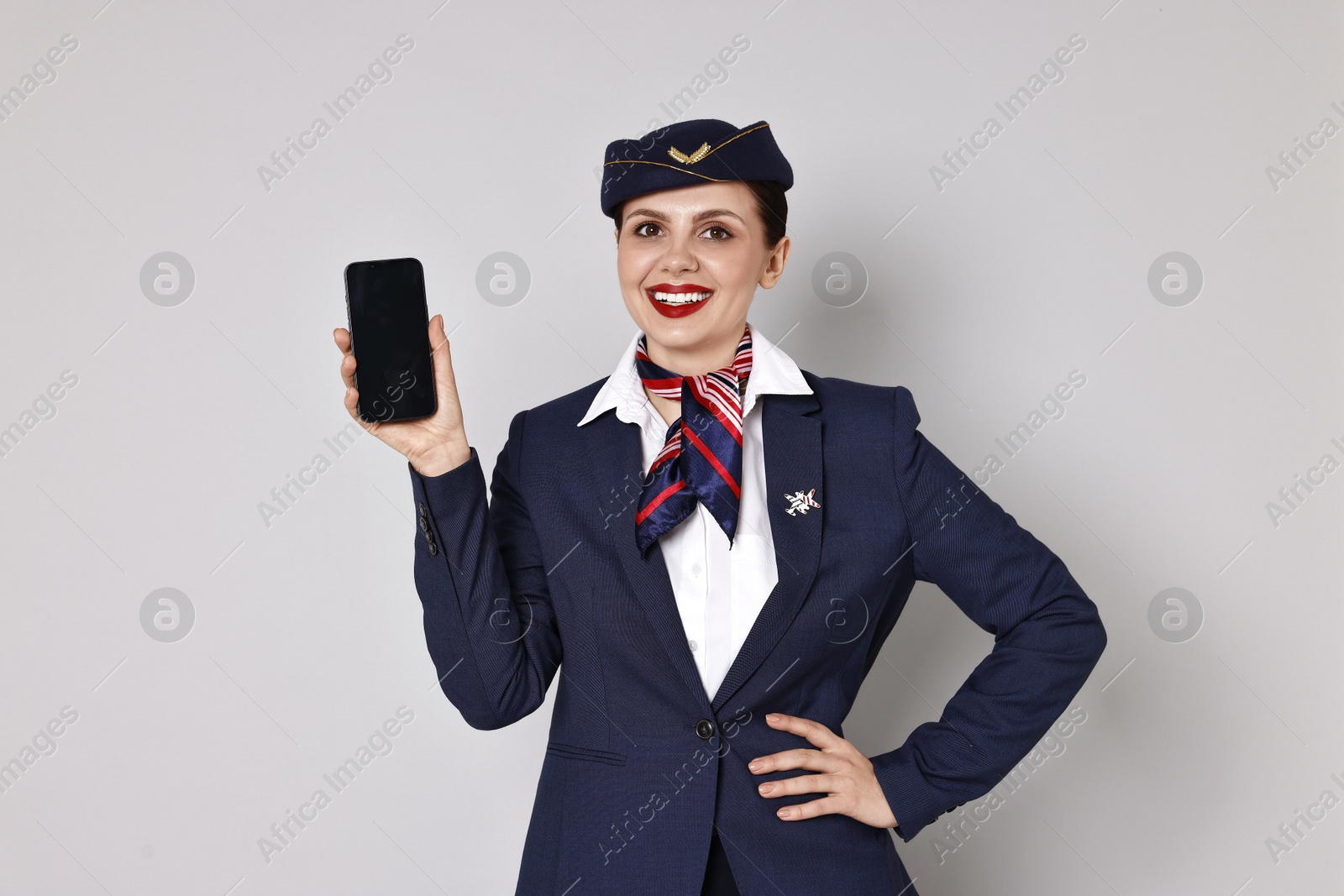 Photo of Smiling stewardess with smartphone on grey background