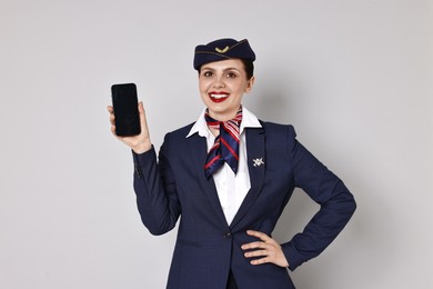 Smiling stewardess with smartphone on grey background