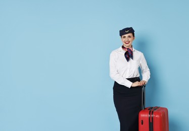 Photo of Smiling flight attendant with suitcase on light blue background. Space for text