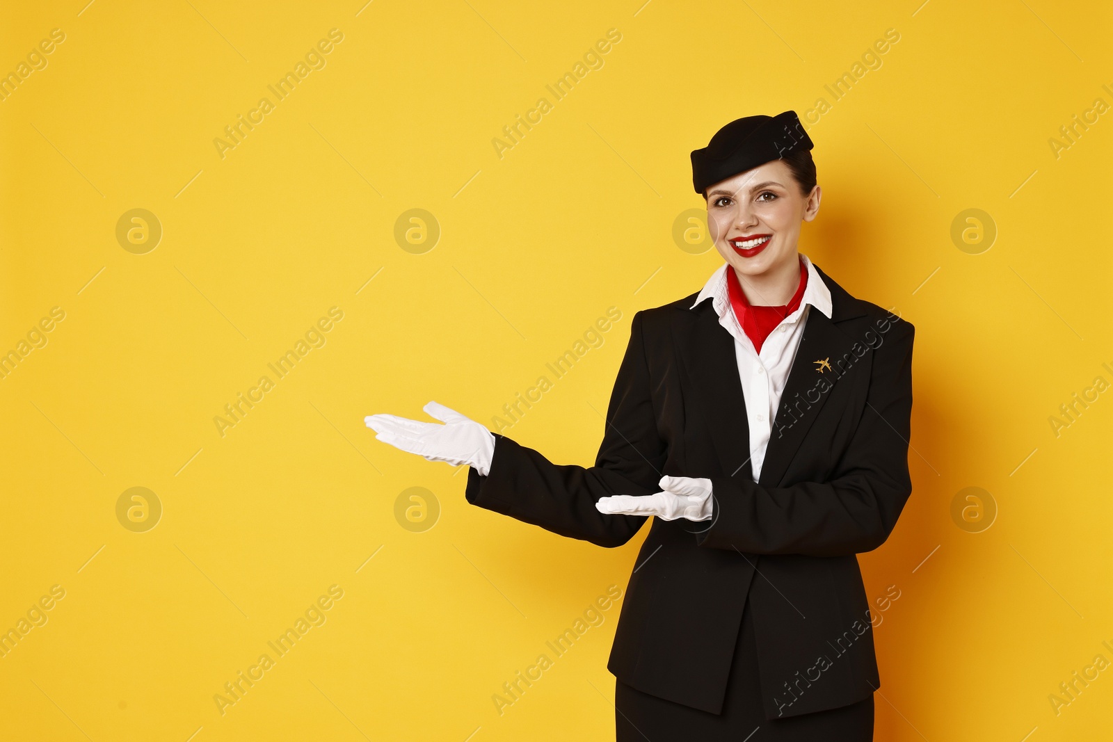 Photo of Happy flight attendant showing something on orange background. Space for text