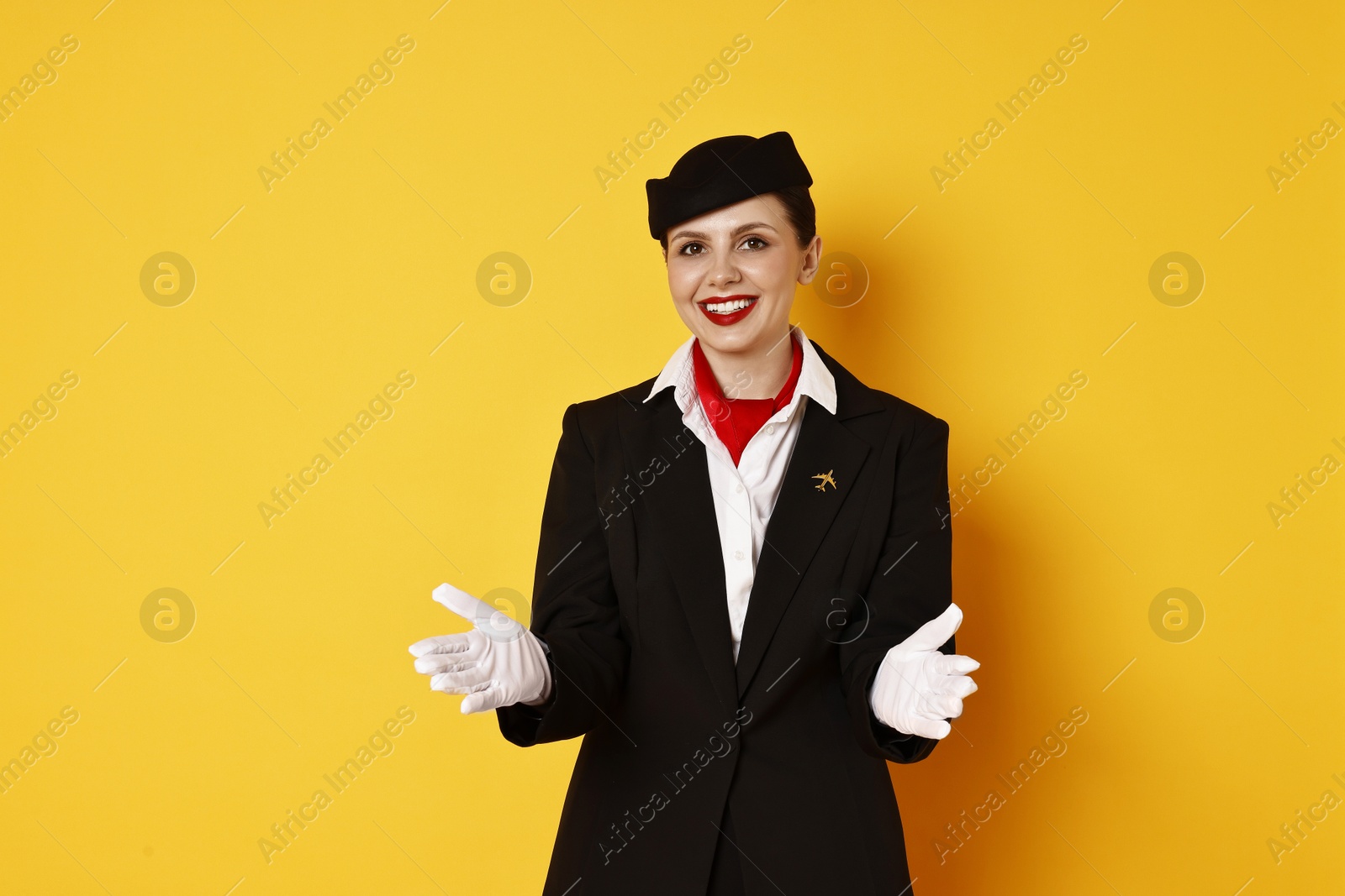 Photo of Smiling flight attendant demonstrating safety instruction on orange background