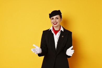 Smiling flight attendant demonstrating safety instruction on orange background