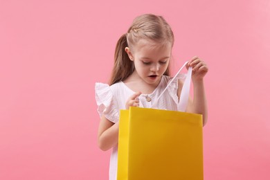 Photo of Little girl with shopping bag on pink background